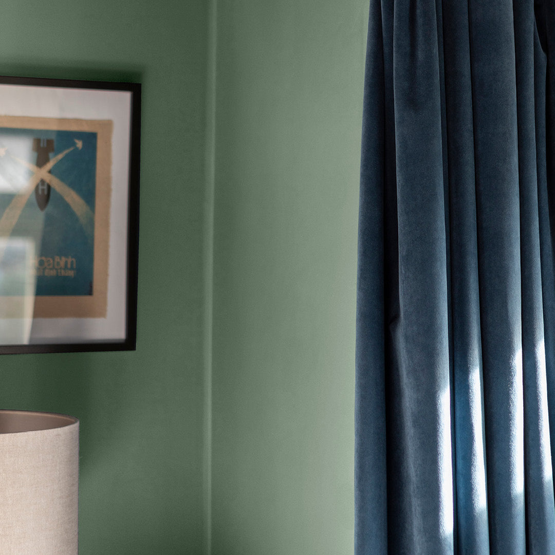 Corner of a living room painted in Zhoosh's Emerald Bay, a pale sage green paint in flat matt. 