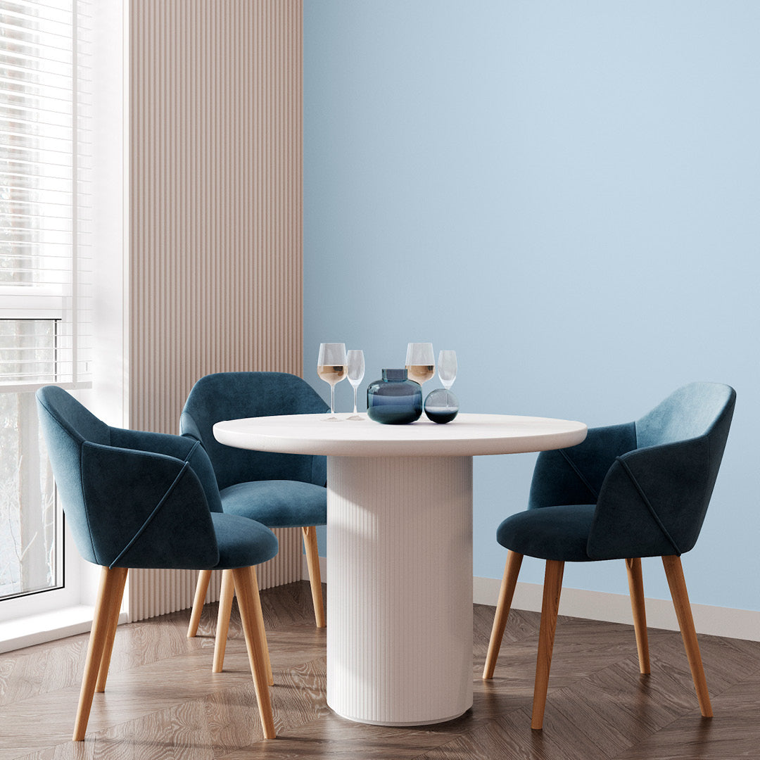 Corner of a living room with a small coffee table and teal chairs, with walls decorated in Glacier, a pastel blue paint from Zhoosh.