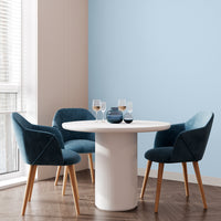 Corner of a living room with a small coffee table and teal chairs, with walls decorated in Glacier, a pale blue paint from Zhoosh.