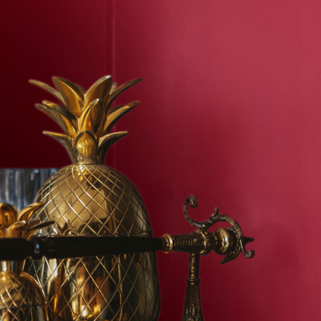 Corner of a living room with an art deco drinks trolley, with walls decorated in Moroccan Market, a blood red paint from Zhoosh.