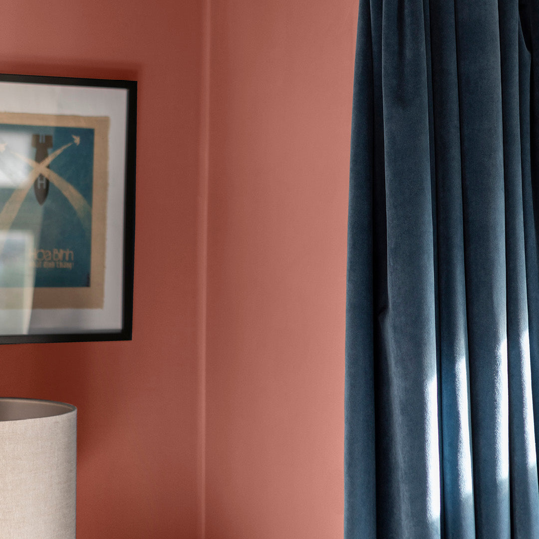 Corner of a living room with walls decorated with Sahara Dust, an earthy red paint from Zhoosh.